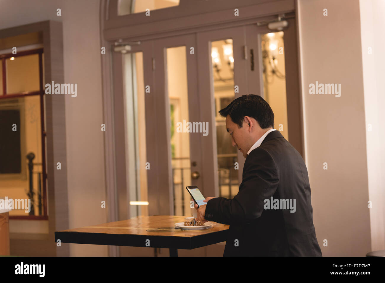Businessman using mobile phone while having coffee Banque D'Images
