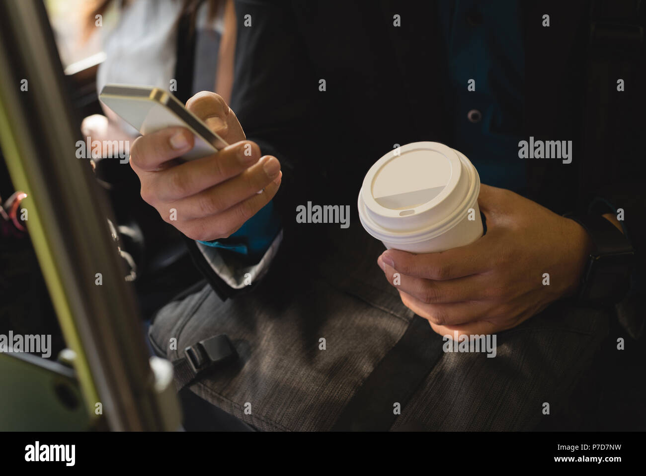 Businessman using mobile phone in bus Banque D'Images