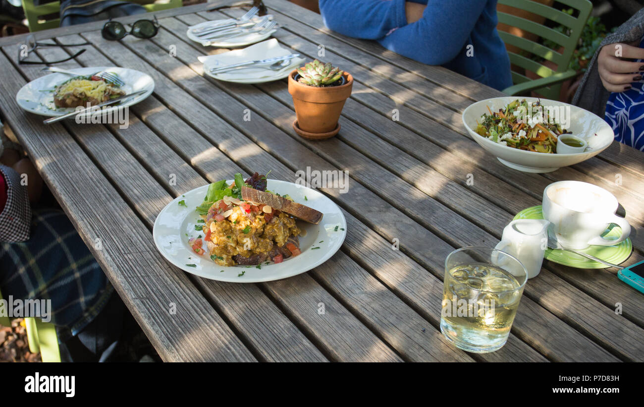déjeuner informel sur une table en bois sous des arbres ombragés avec des assiettes saines de concept alimentaire authentique de style de vie des femmes Banque D'Images