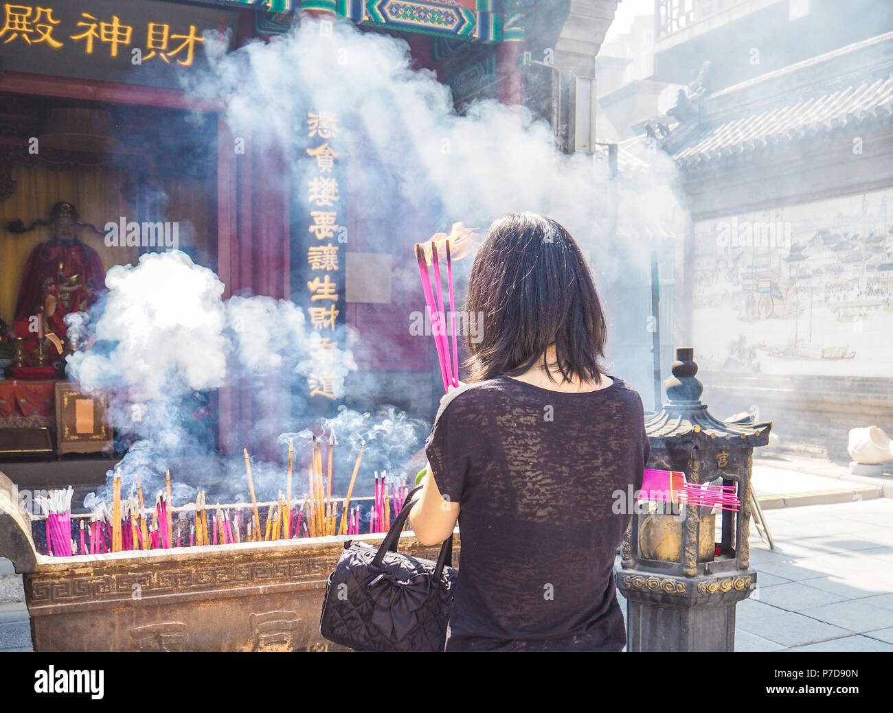 Jeune femme tenant les grandes d'encens brûlant tout en priant au temple taoïste de la Reine du Ciel, Tianjin, Chine Banque D'Images