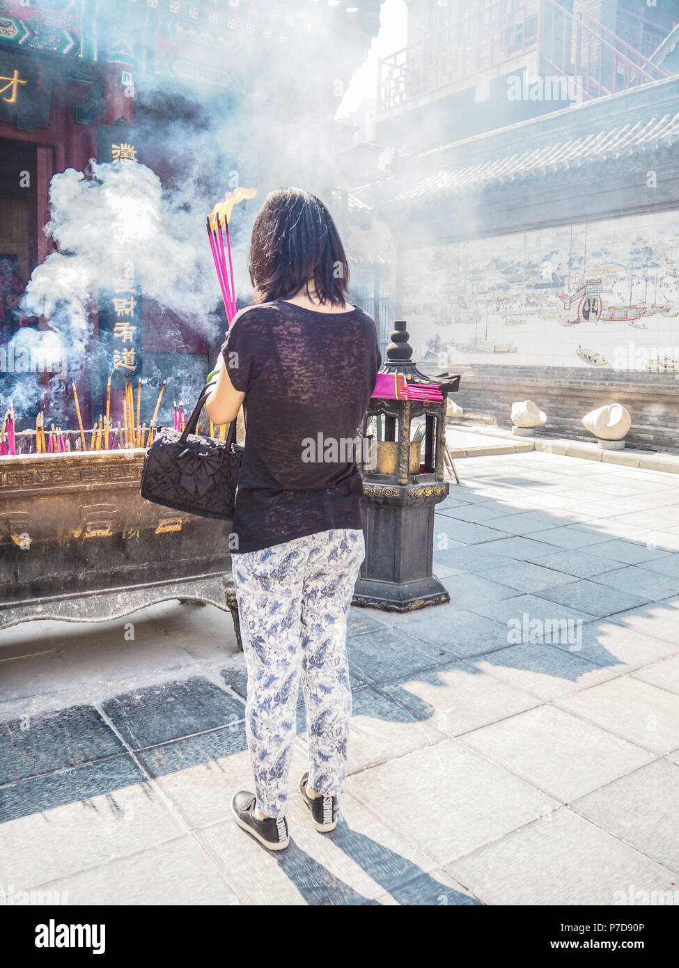 Jeune femme tenant les grandes d'encens brûlant tout en priant au temple taoïste de la Reine du Ciel, Tianjin, Chine Banque D'Images