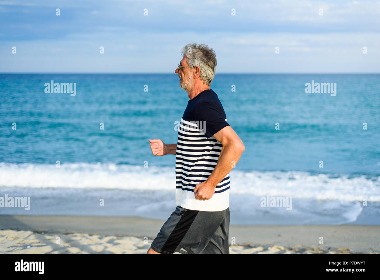 Hauts homme qui court sur la plage, style de vacances actives Banque D'Images