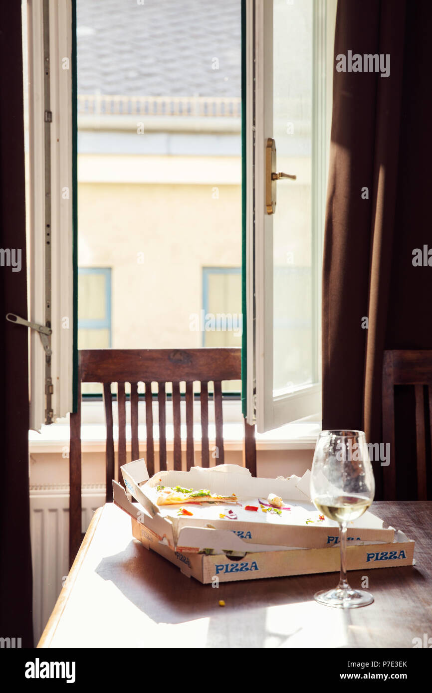 Les restes de pizza en boîte et verre de vin sur la table à manger Banque D'Images