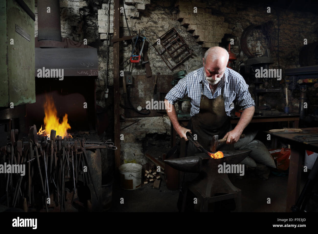 Blacksmith hammering red hot metal de forgerons shop Banque D'Images