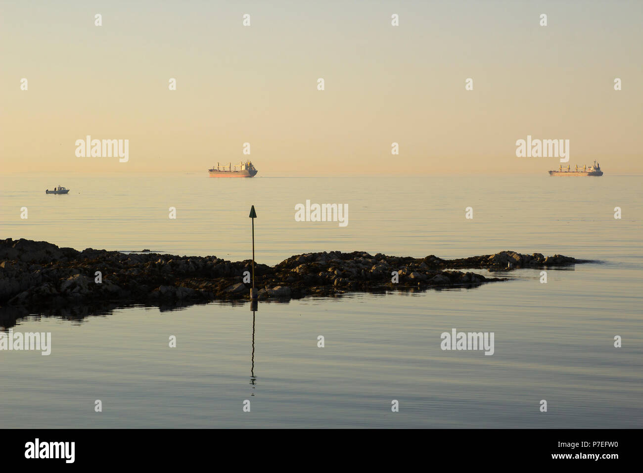 Les navires à l'ancre à l'embouchure de Belfast Lough alors que le soleil se couche sur l'entrée de Groomsport Village Harbour en Irlande du Nord Banque D'Images