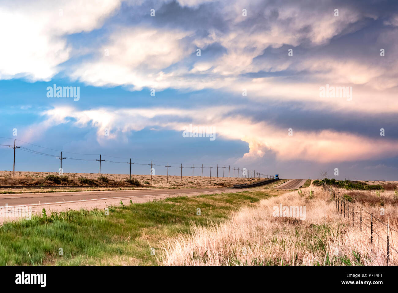 Une route à distance dans les Grandes Plaines dans Tornado Alley montre un très subtil coucher du soleil le long d'un chemin herbeux comme les lignes rose coucher de soleil pour la journée. Banque D'Images