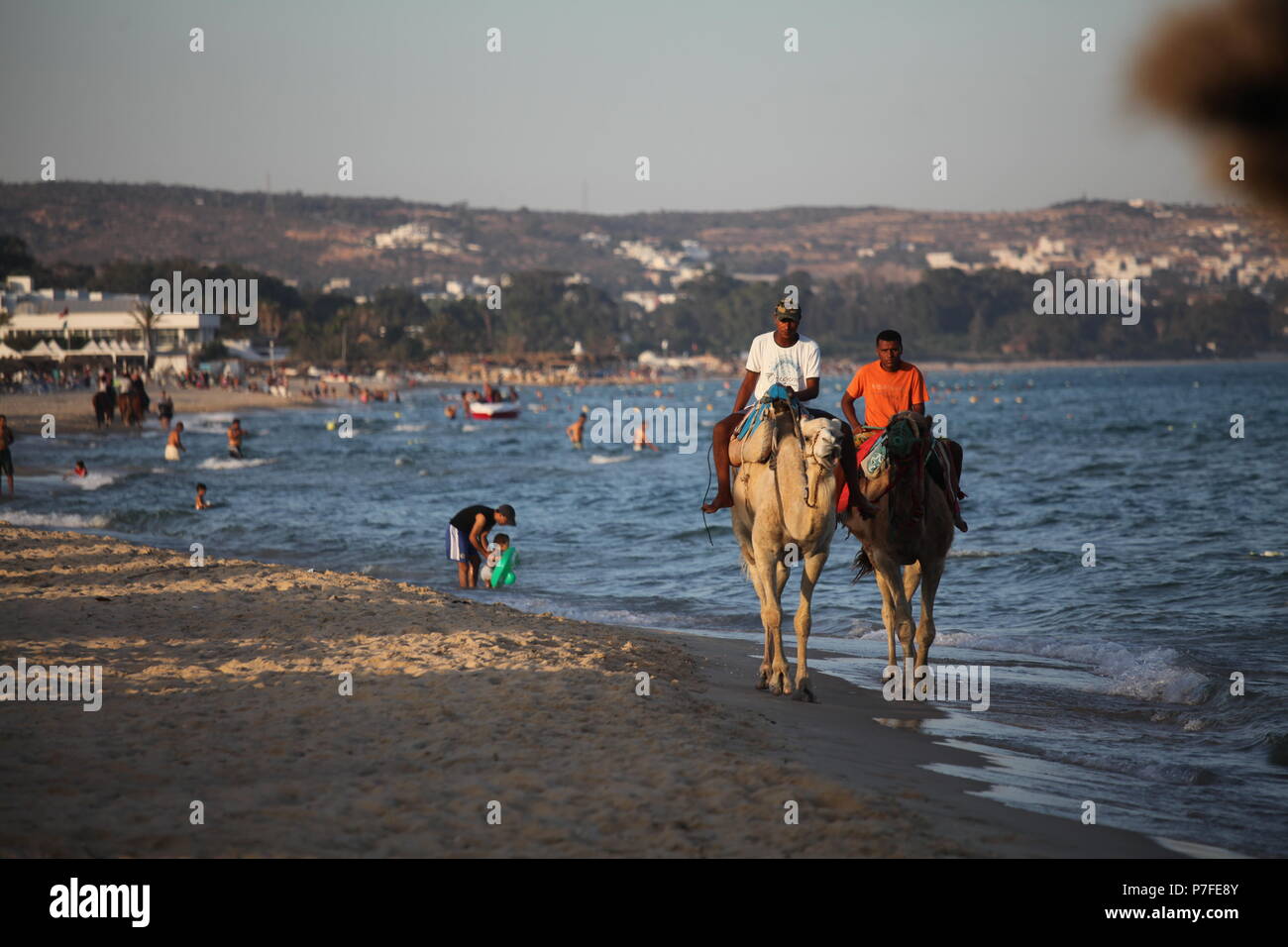 Deux tunisiens monter des chameaux sur la côte méditerranéenne, en proposant les touristes à essayer cette attraction exotique, pour ceux qui ont eu assez de la natation et la plongée Banque D'Images