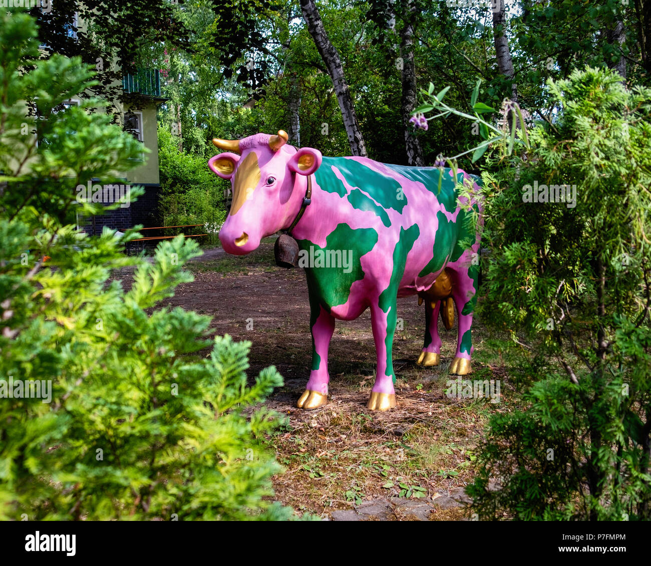 Berlin-Dahlem.statue de vache rose et vert avec bell pairs au moyen d'arbustes dans le jardin Banque D'Images