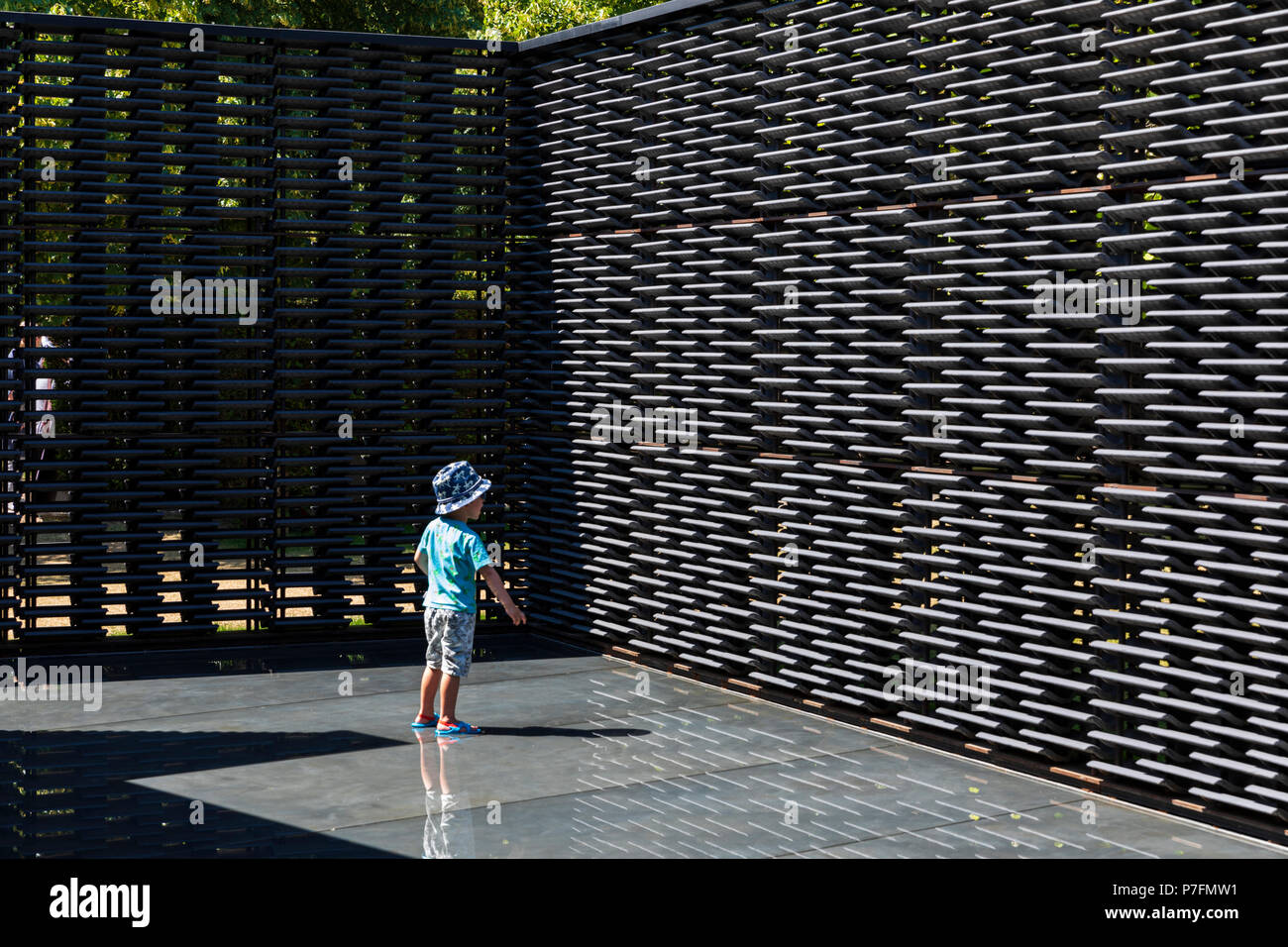 Un jeune garçon se trouve dans le bassin intérieur de la Serpentine Pavilion 2018 conçu par l'architecte Frida Escobedo. Banque D'Images