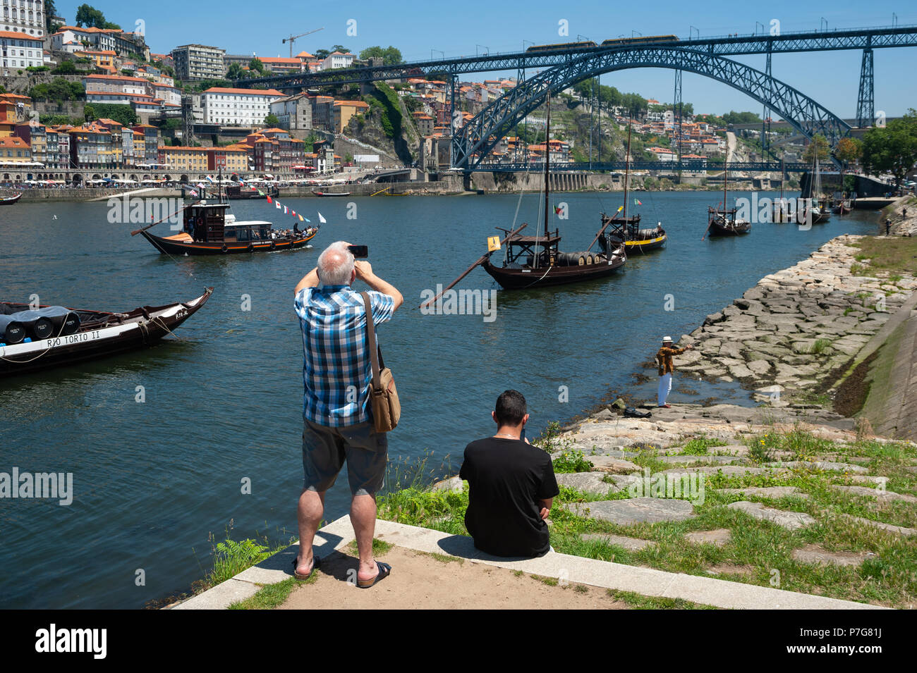 14.06.2018, Porto, Portugal, Europe - un touriste prend des photos à la banque de la rivière Douro avec le Pont Dom Luis I dans la toile. Banque D'Images