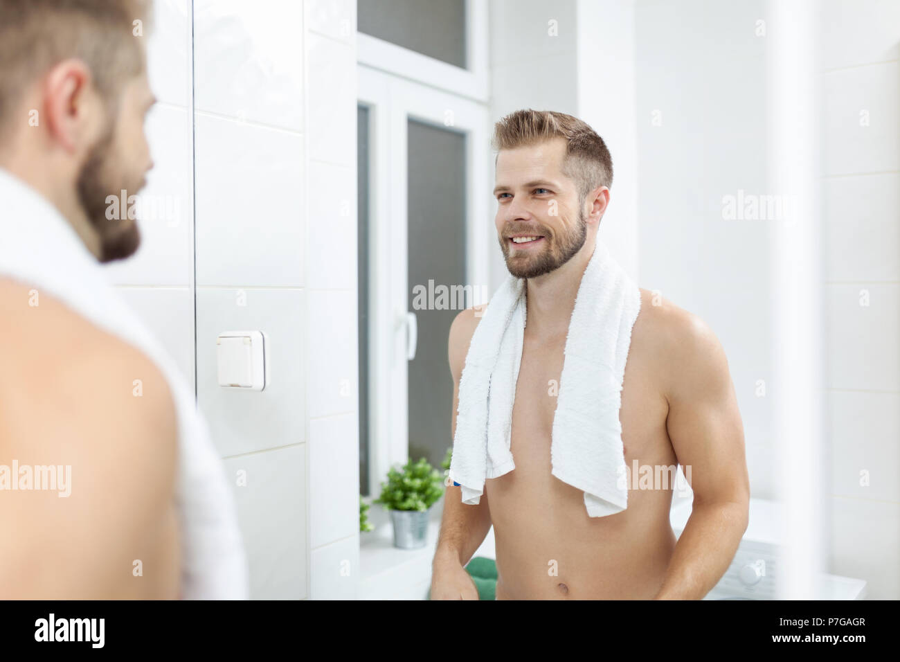 Matin l'hygiène, bel homme dans la salle de bains à la recherche dans le miroir Banque D'Images