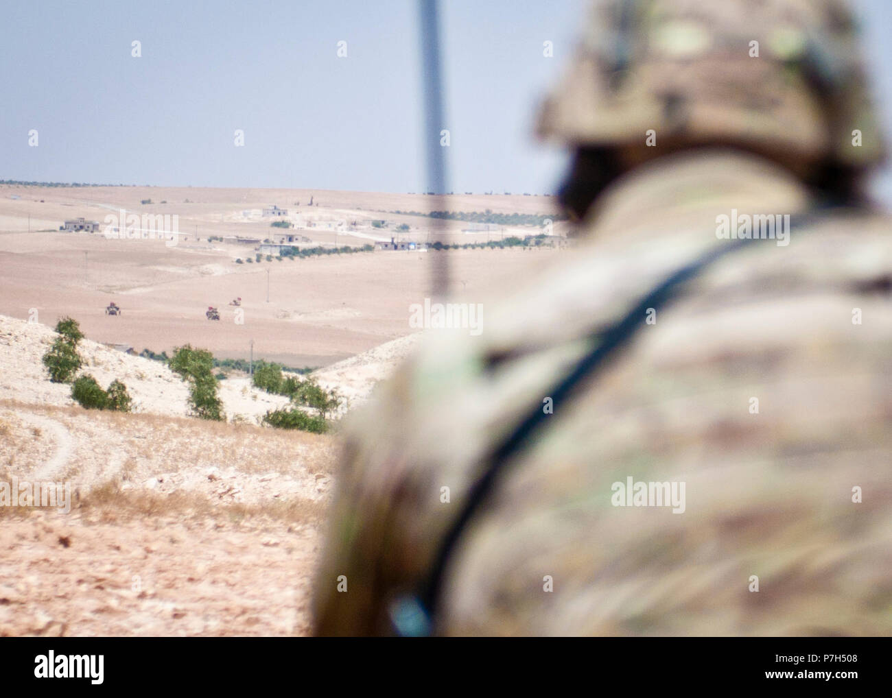 Un soldat américain utilise une radio pour communiquer avec les forces  militaires turques pendant leur patrouille indépendante, coordonnée le long  de la ligne de démarcation en dehors de Manbij, Syrie, 28 juin