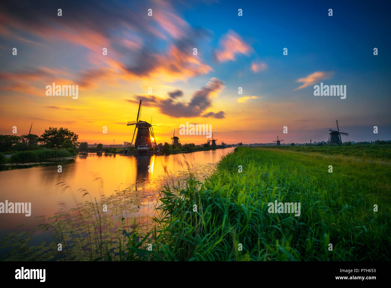 Magnifique coucher de soleil au-dessus de vieux moulins à vent hollandais et un canal à Kinderdijk, Pays-Bas. Longue exposition. Banque D'Images