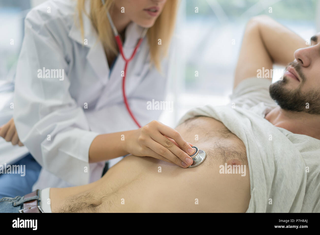 Belle femme médecin en blanc manteau médical examine un patient avec un stéthoscope à l'hôpital. Soins médicaux et concept. Banque D'Images