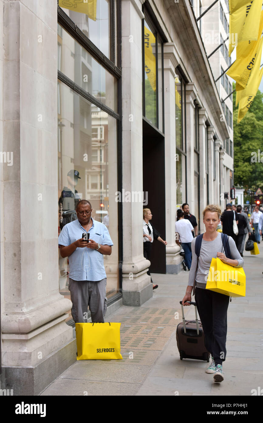 Consommateurs et aux touristes shopping à pied passé le grand magasin Selfridges sur Oxford Street, au centre de Londres. Banque D'Images