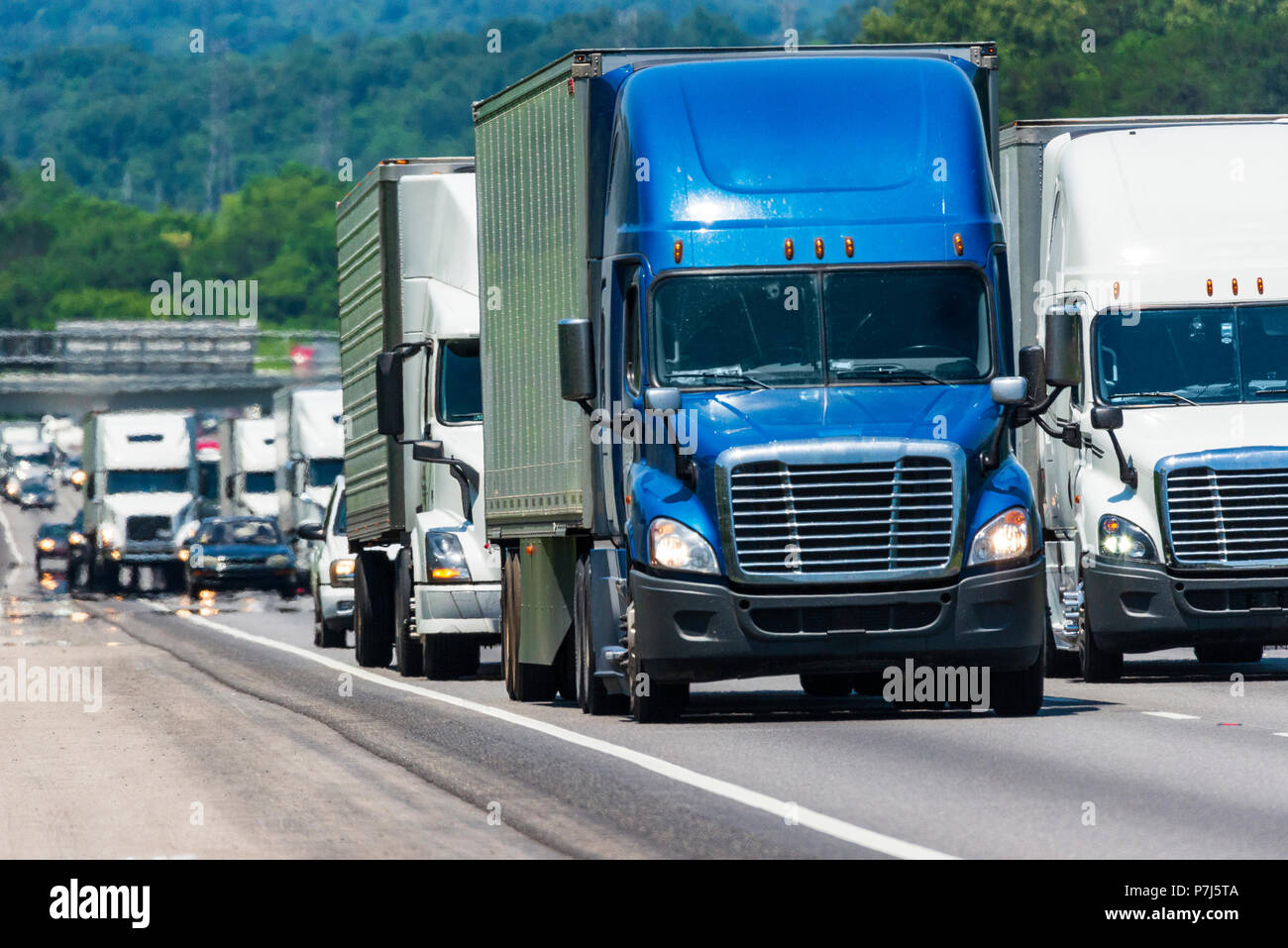 Une longue ligne d'équilibre de la circulation des camions sur une autoroute. Capture d'image sur chaude journée. Les vagues de chaleur de l'asphalte créer de distorsion, en particulier sur les véhicules loin Banque D'Images