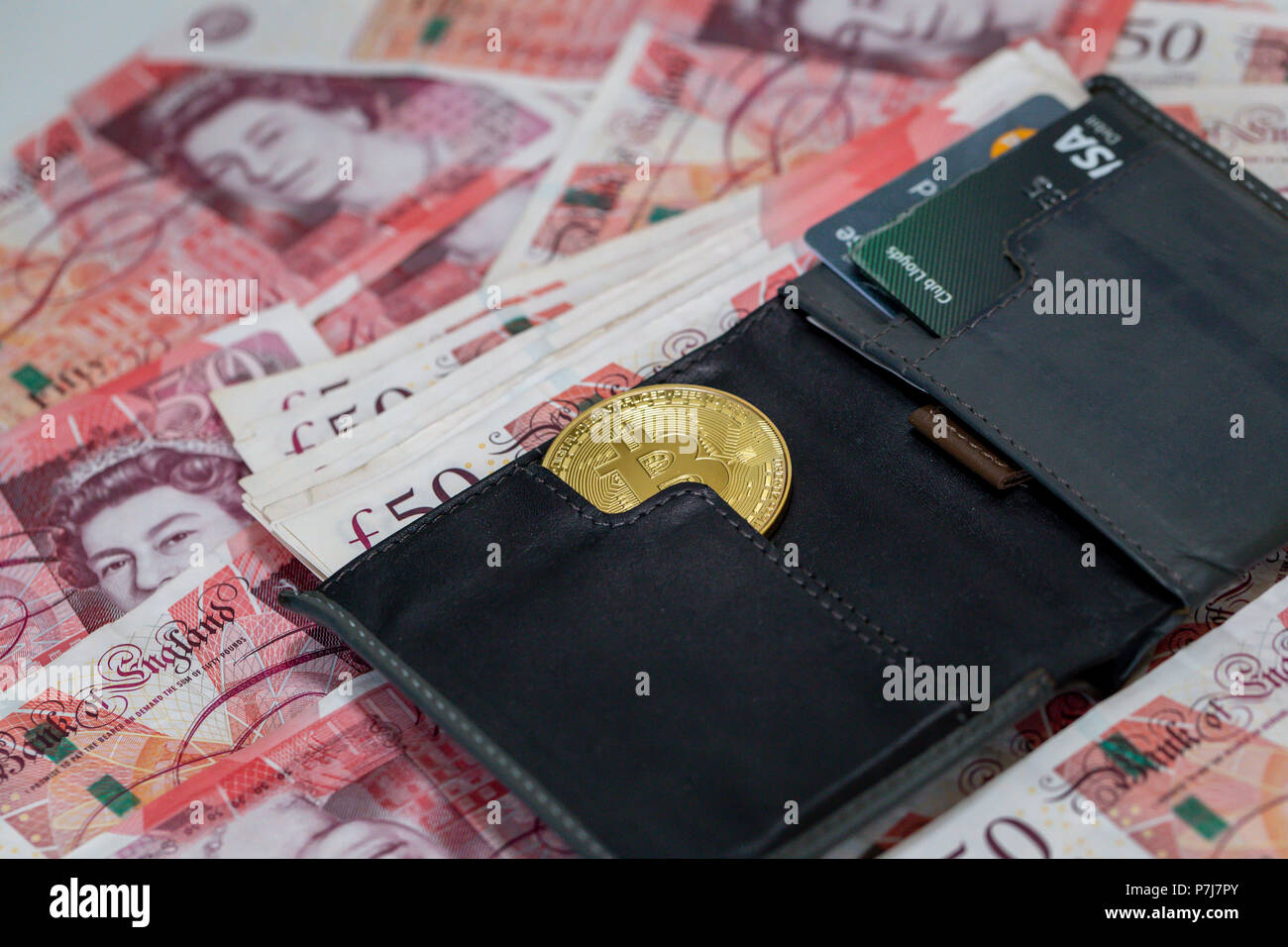 Un étui contenant un bitcoin et 50 livre sterling bank notes sur un grand tas de plus de cinquante livres billets utilisés Banque D'Images
