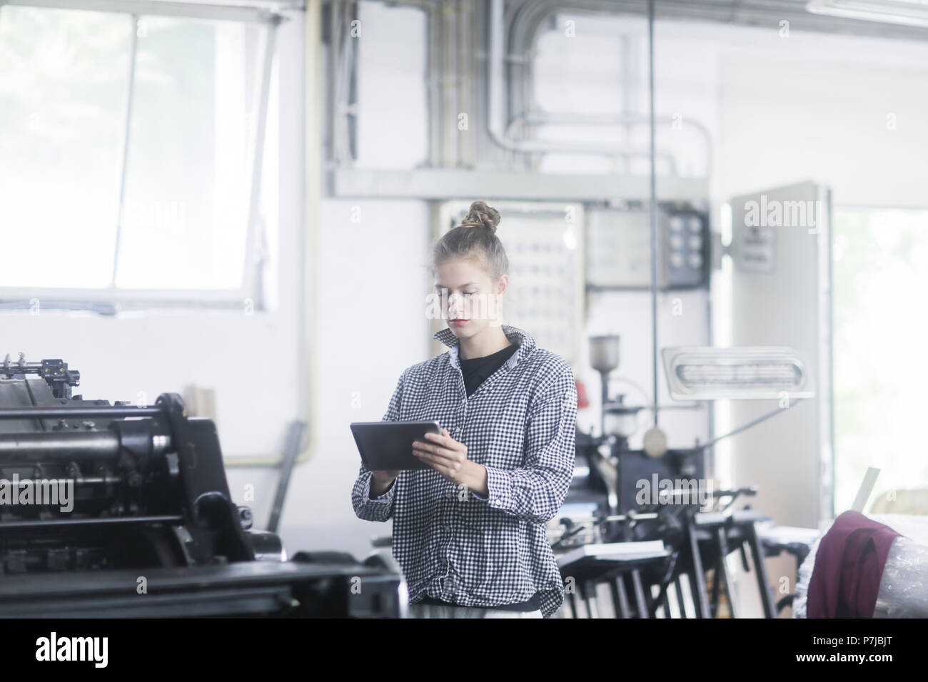 Femme debout dans un atelier à l'aide d'une tablette numérique Banque D'Images