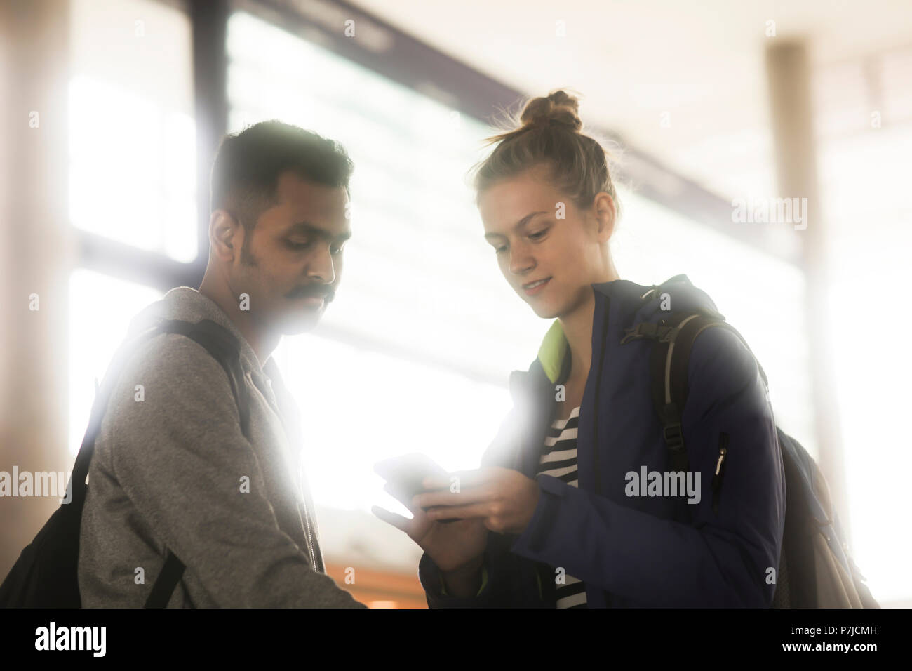 Couple debout devant une arrivée départ à la carte à un téléphone mobile Banque D'Images