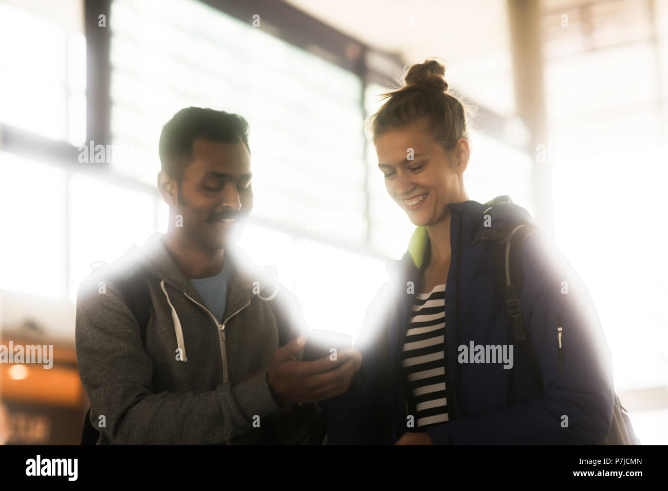 Smiling Couple debout devant une arrivée départ à la carte à un téléphone mobile Banque D'Images