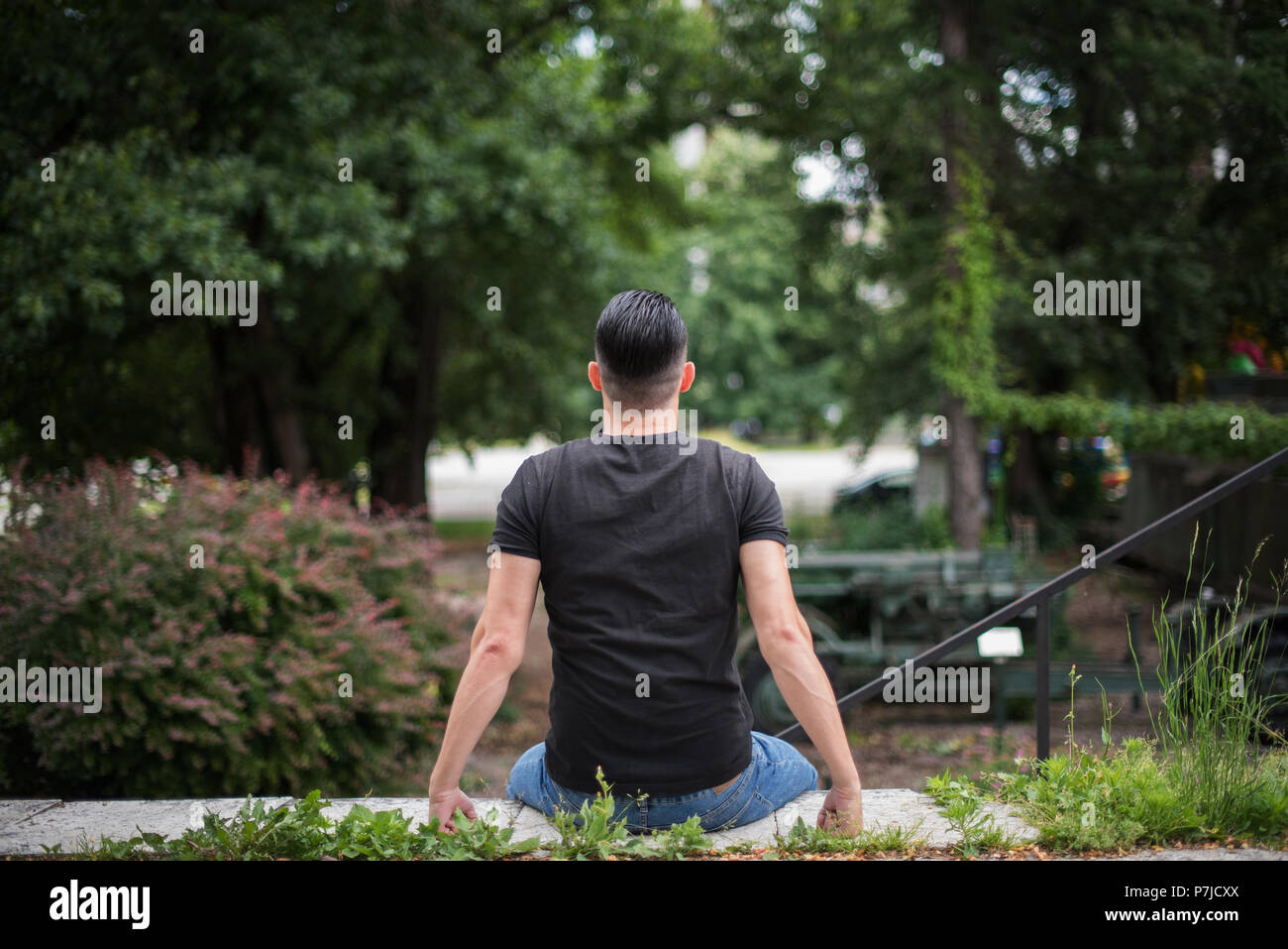 Homme assis sur un banc dans un parc public Banque D'Images