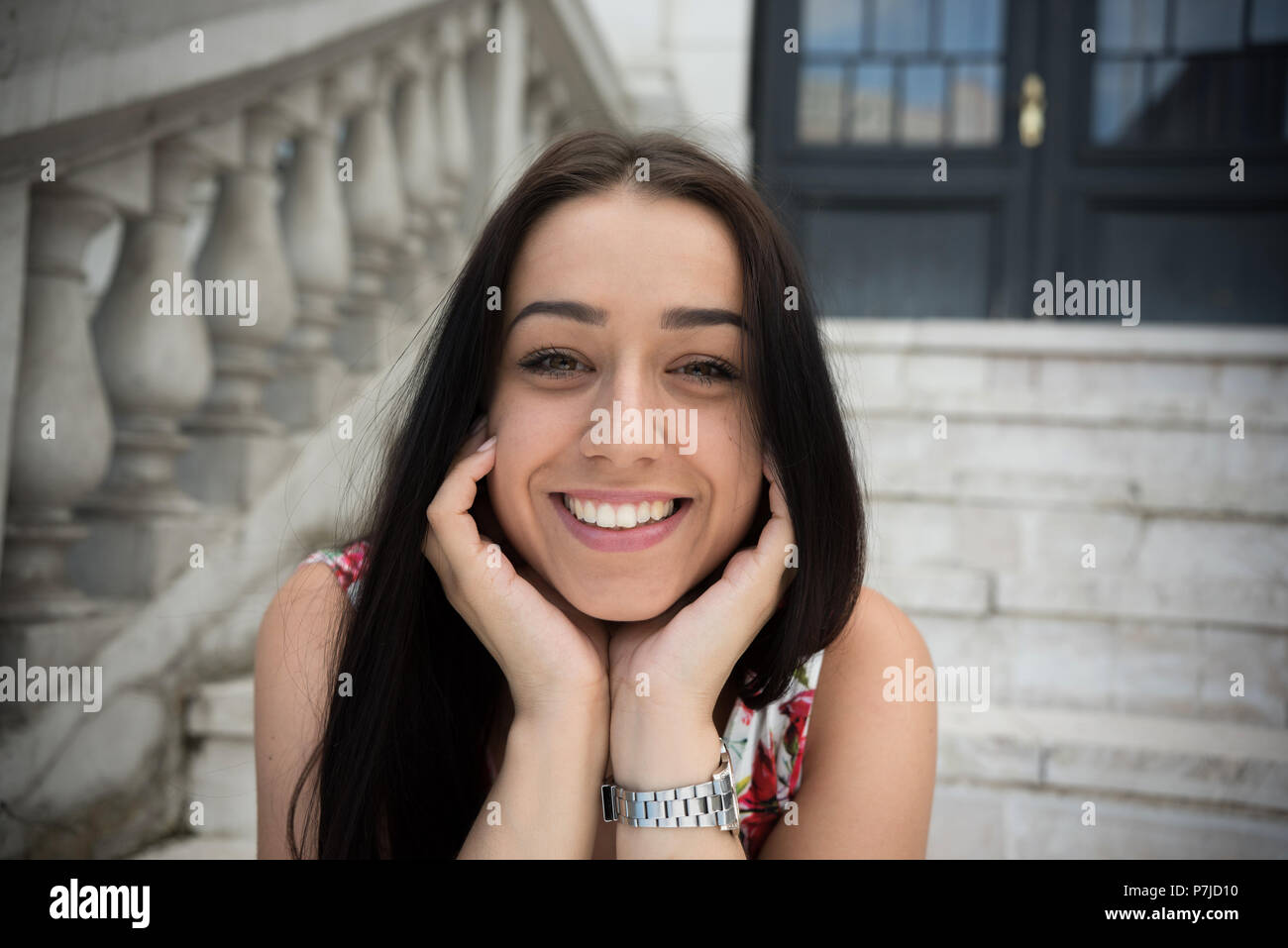 Portrait of a smiling woman sitting on steps à l'extérieur d'un bâtiment Banque D'Images