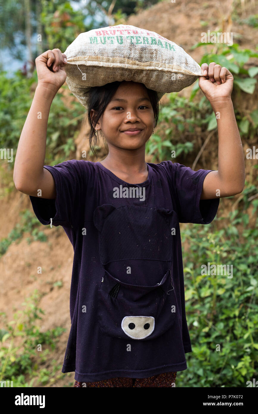 Fille indonésien transportant un sac sur sa tête, demi-portrait Banque D'Images