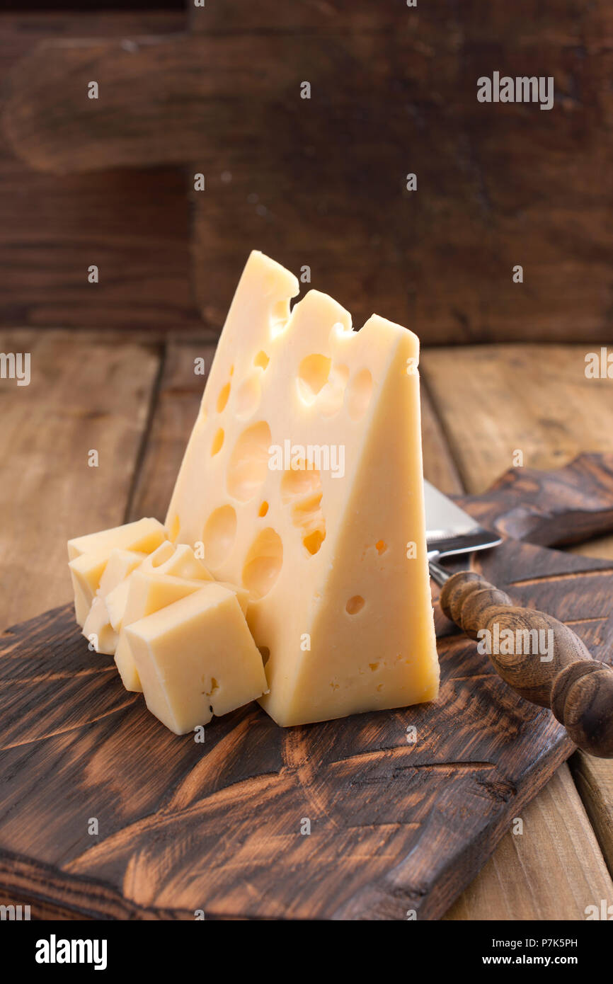 Fromage hollandais traditionnel avec des trous, sur une planche en bois vintage, fond de bois. Les produits laitiers. Copy space Banque D'Images