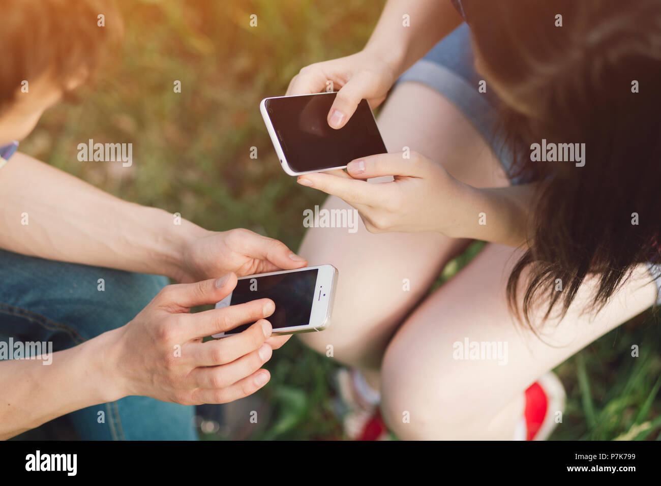 Couple de personnes dans park en utilisant des téléphones. Banque D'Images