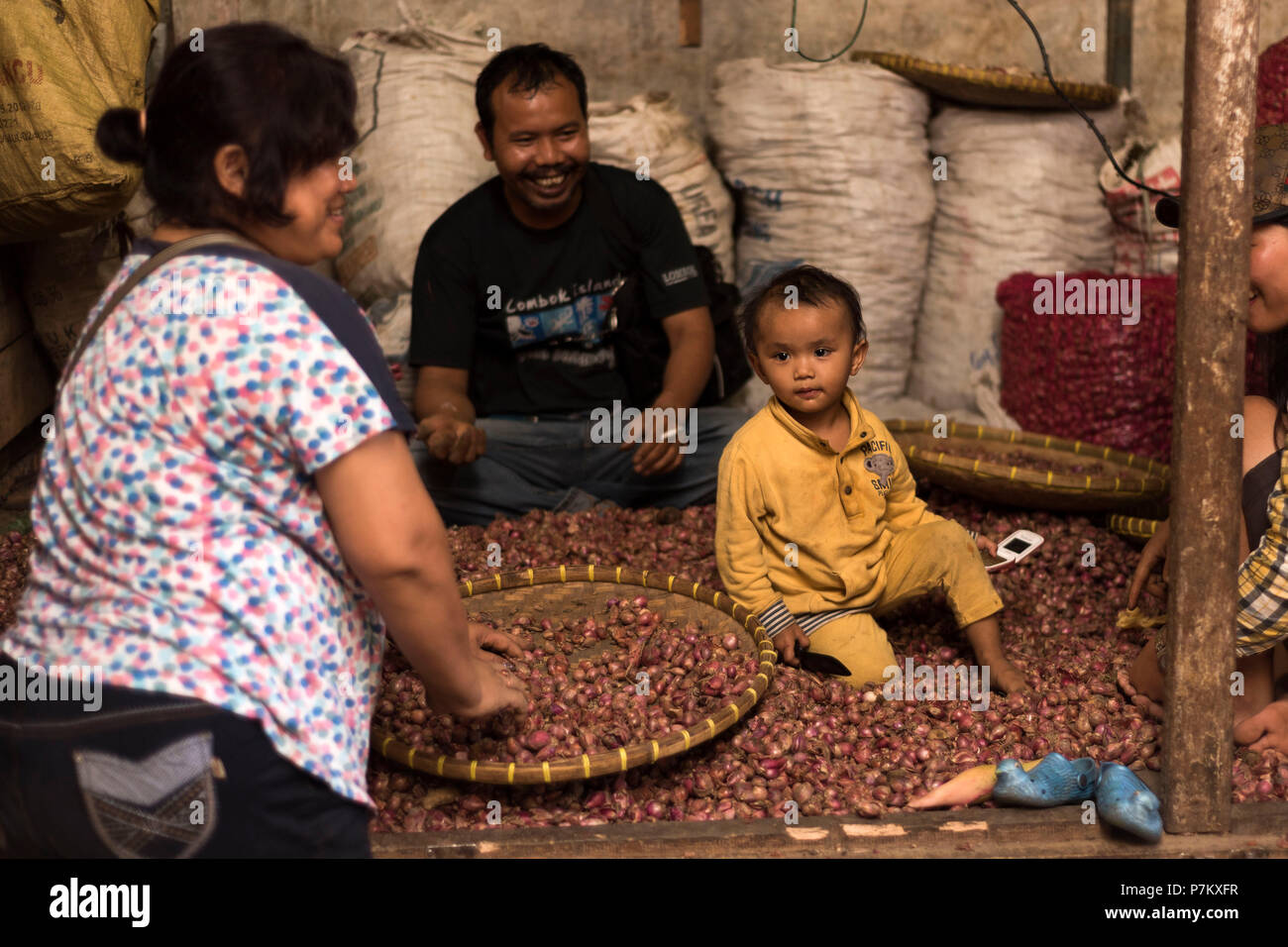 Un enfant assis dans le stand de Kutacane entre beaucoup d'oignons dans sa famille, de l'échoppe de marché Banque D'Images