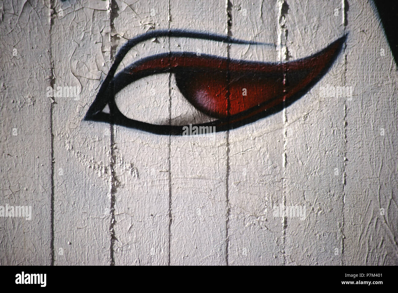 Une femme peint par pulvérisation ou avec les élèves de l'oeil rouge sur un mur de béton. Banque D'Images