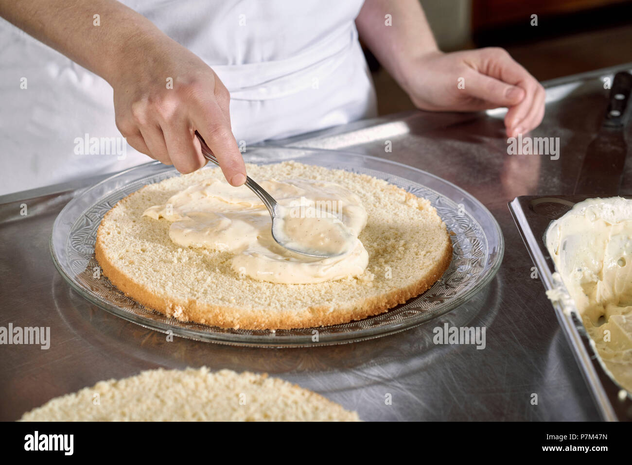 Des mesures pour faire un gâteau à la framboise, répandre la crème vanille sur les tranches de biscuit ? ? Banque D'Images