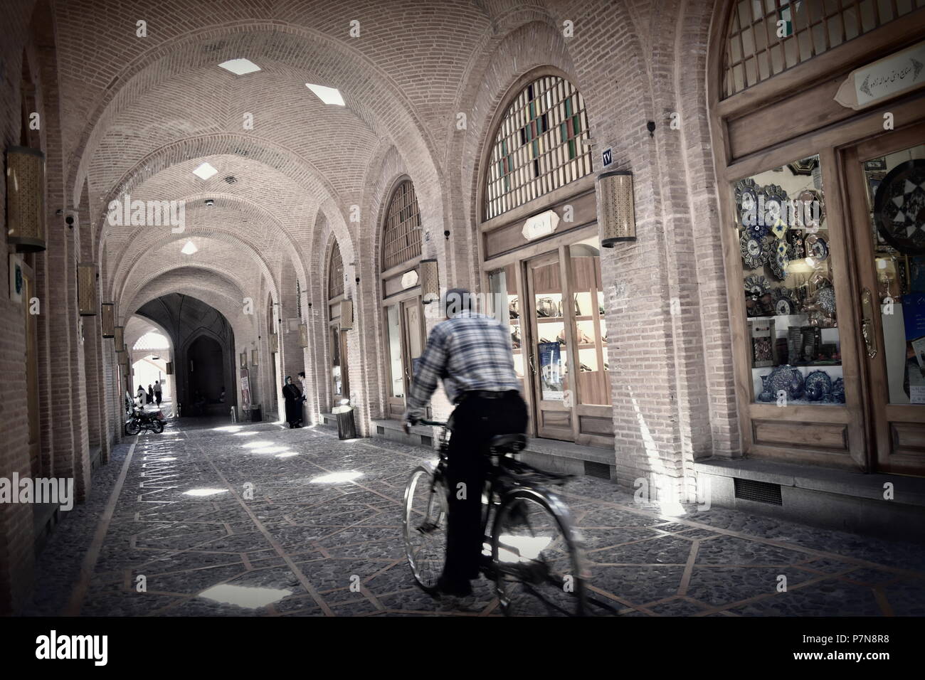 Man rides vieux vélo le long des allées de l'ère de la route de la soie traditionnelle Moyen Orient bazar marché de Qazvin, en Iran Banque D'Images