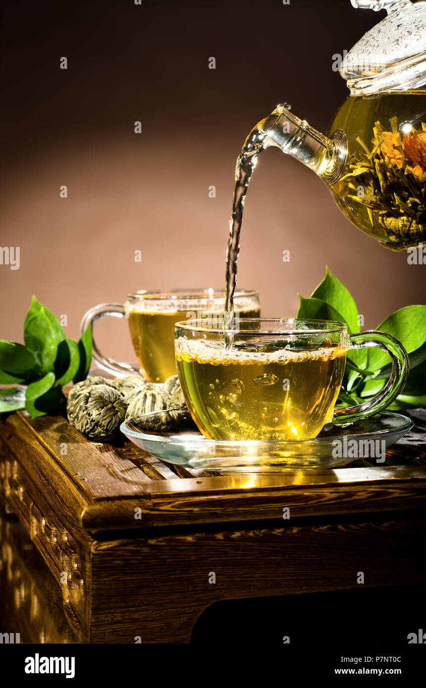 Photo verticale, de la théière en verre tasse thé vert en débit sur fond brun, cérémonie du thé Banque D'Images