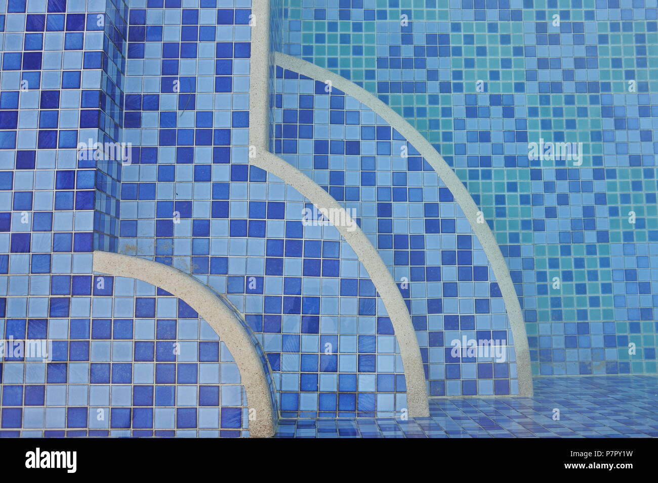 Une vue de dessus captivante d’une piscine ornée de carreaux bleus pixélisés, créant un effet dégradé. Le point focal est sur trois quarts de cercle-sh Banque D'Images