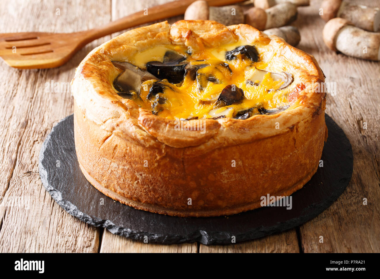 Tarte fraîchement cuits, de la quiche avec cèpes, fromage cheddar, du poulet et de la crème sur la table horizontale. Banque D'Images