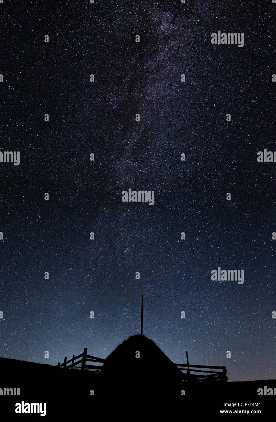 Silhouette d'une pile de paille contre le ciel de nuit avec les étoiles et la Voie lactée visible Banque D'Images