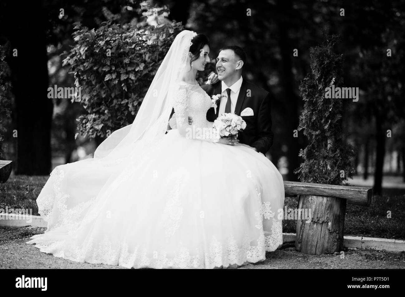 Couple nouvellement marié assis dans le parc sur le versant ensoleillé de l'été jour de mariage. Photo en noir et blanc. Banque D'Images