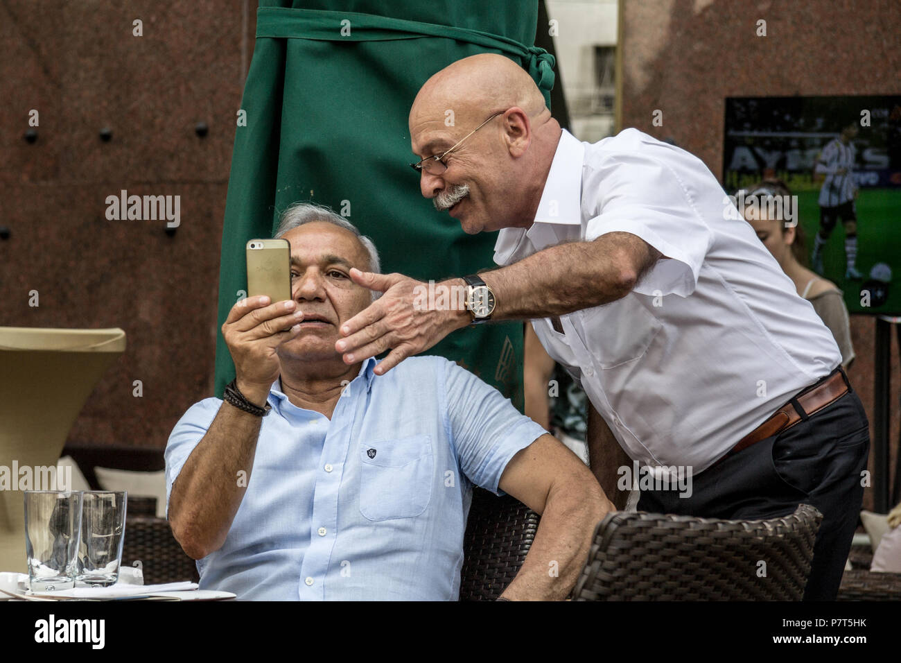 BELGRADE, SERBIE - 14 juin 2015 : deux vieux hommes blancs sernior assis dans un café à la recherche d'un Apple IPhone smartphone, l'une expliquant le deuxième comment Banque D'Images