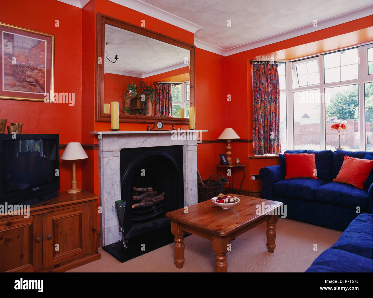 Canapés bleu vif et une table basse en pin 80 orange salon avec grand miroir au-dessus de cheminée en marbre Banque D'Images