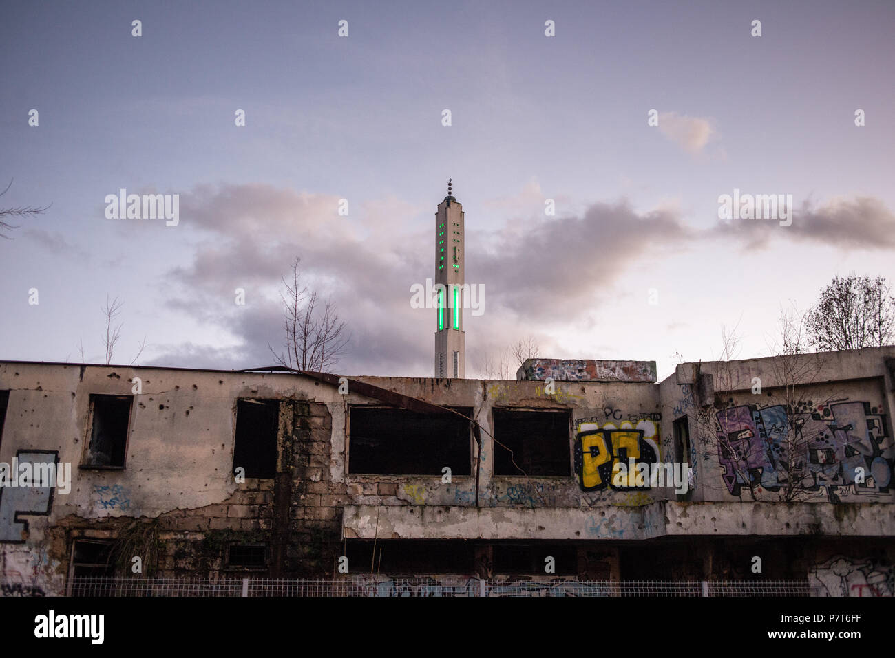 Minaret de la mosquée derrière le bâtiment endommagé par les bombardements de l'artillerie de la guerre civile en Bosnie, Sarajevo, Bosnie et Herzégovine Banque D'Images