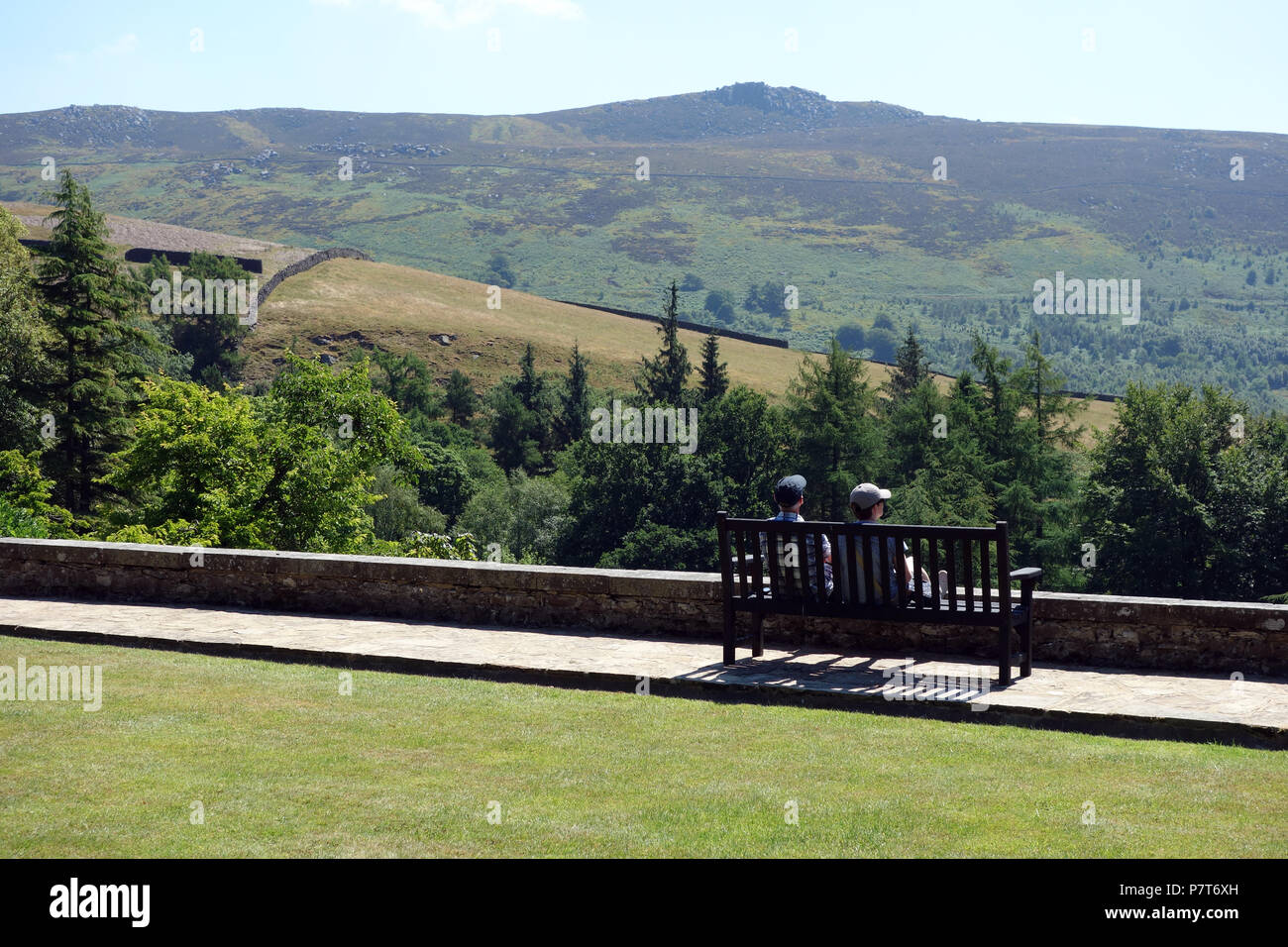 Un couple assis sur un banc en bois à l'Université Simon du siège conducteur en Parcevall Hall Gardens, Skyreholme, Appletreewick, Wharfedale, Yorkshire, Angleterre, Royaume-Uni. Banque D'Images