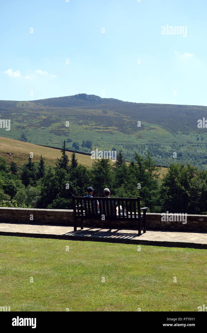 Un couple assis sur un banc en bois à l'Université Simon du siège conducteur en Parcevall Hall Gardens, Skyreholme, Appletreewick, Wharfedale, Yorkshire, Angleterre, Royaume-Uni. Banque D'Images