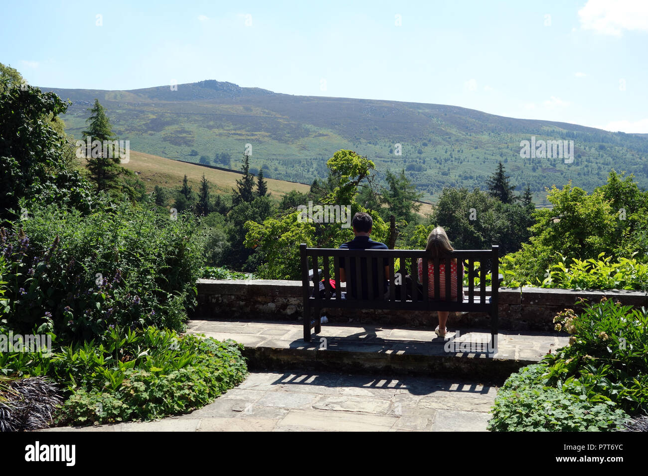 Un couple assis sur un banc en bois à l'Université Simon du siège conducteur en Parcevall Hall Gardens, Skyreholme, Appletreewick, Wharfedale, Yorkshire, Angleterre, Royaume-Uni. Banque D'Images