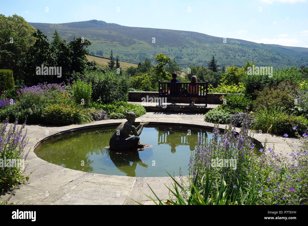 Un couple assis sur un banc en bois à l'Université Simon du siège conducteur en Parcevall Hall Gardens, Skyreholme, Appletreewick, Wharfedale, Yorkshire, Angleterre, Royaume-Uni. Banque D'Images