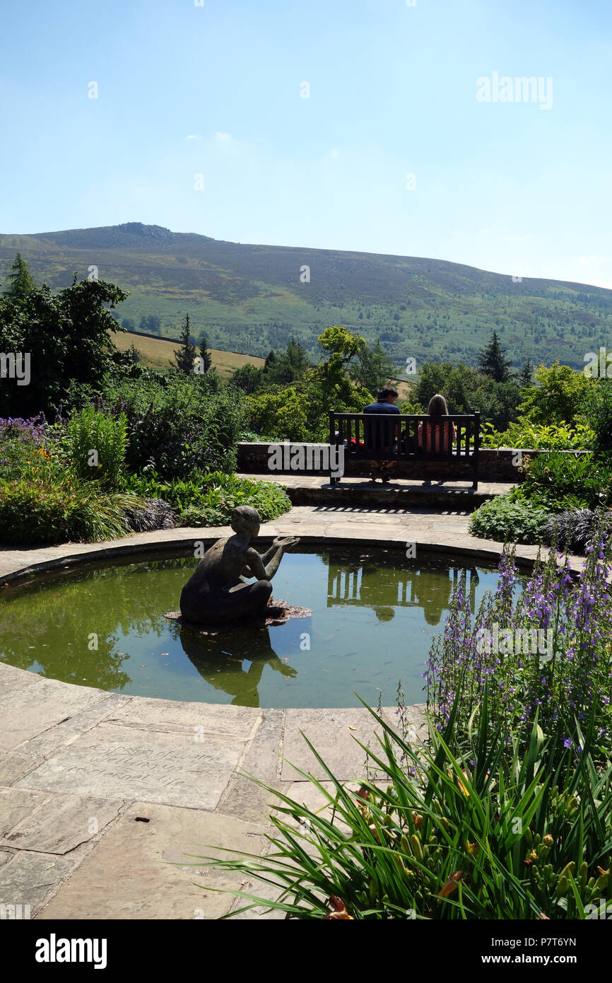 Un couple assis sur un banc en bois à l'Université Simon du siège conducteur en Parcevall Hall Gardens, Skyreholme, Appletreewick, Wharfedale, Yorkshire, Angleterre, Royaume-Uni. Banque D'Images