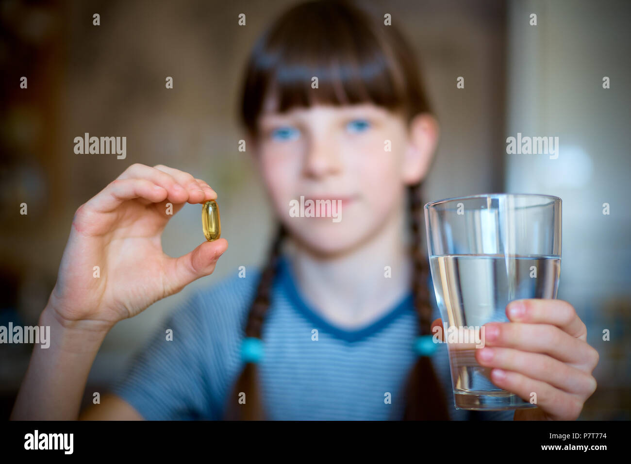 Gélules, comprimés dans une main, un verre d'eau dans l'autre. La fille est maintenant la médecine en face d'elle. Close-up. Banque D'Images