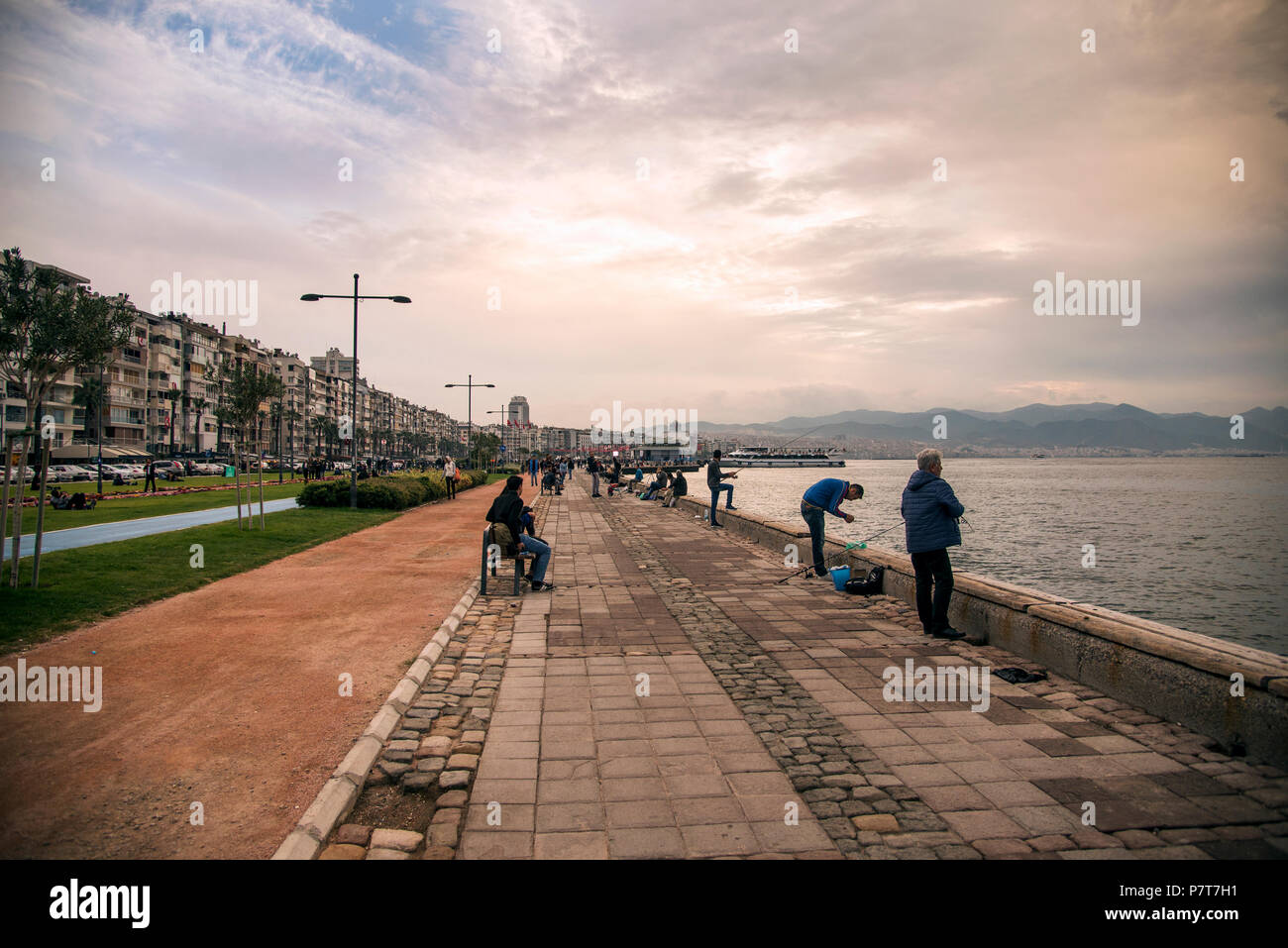 Izmir, Turquie - 28 octobre 2017 : vue sur Izmir Alsancak ferry et les gens assis près de la pêche et en bord de l'eau avec temps nuageux. Banque D'Images