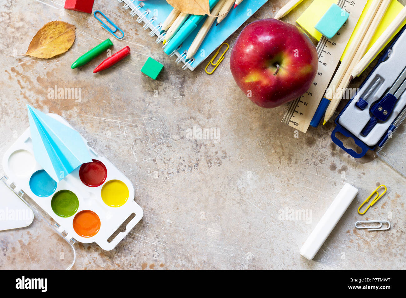 Retour à l'école. Les fournitures scolaires, apple et origami avion sur une pierre ou l'ardoise. Banque D'Images