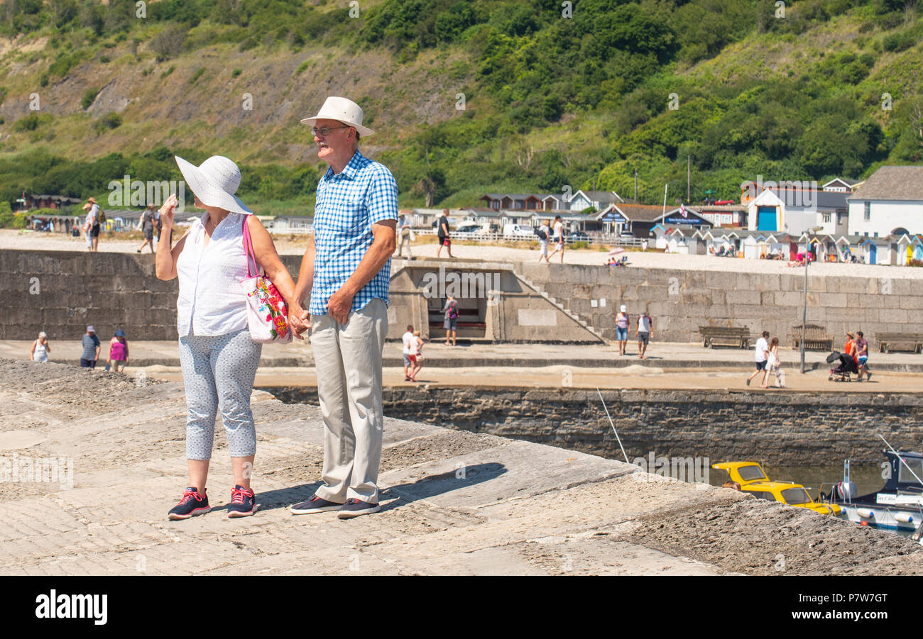 Lyme Regis, dans le Dorset, UK. 8e juillet 2018. Météo France : Un autre brulante et dimanche ensoleillé à Lyme Regis. La Côte Jurassique rôtis de nouveau comme les visiteurs et les gens affluent à la plage sur une autre animation de dimanche sur la côte sud. Un couple se promener le long de l'emblématique Cobb dans la lumière du soleil chaude. Credit : Celia McMahon/Alamy Live News Banque D'Images
